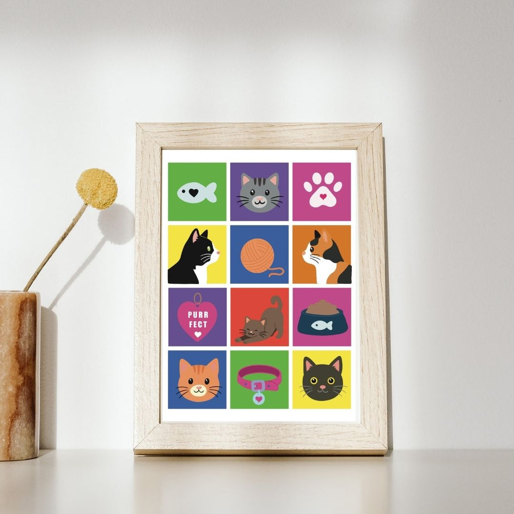 Hand-drawn cat art print framed in tan leaning on shelf wall featuring a colorful grid of cat illustrations including tabby cats, a tuxedo cat, a calico cat, a fish, yarn ball, paw print, cat collar, food bowl, and a 'Purrfect' heart tag — by JC Pet Designs. Frame not included.