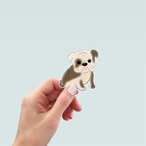 hand holding a cute hand-drawn bulldog puppy sticker with a soft beige and brown coat