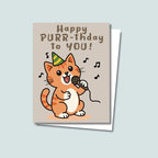 Happy Purr-thday birthday card featuring an orange cat with tan belly standing up with microphone in left paw and green & yellow party hat on and musical notes floating around cat, text on top of card reads "Happy Purr-thday to You", the card has a muted light brown background