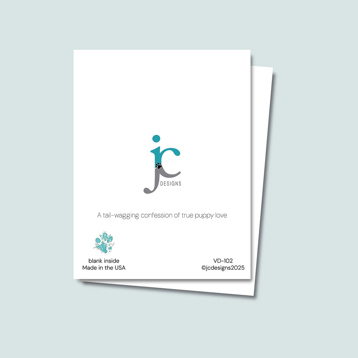 back of Mutts About You Valentine's Day card showing JC Pet Designs logo and unique tagline that reads "A tail-wagging confession of true puppy love", in bottom left corner of the white card is Oz's paw print in teal and text that reads "blank inside, made in the USA", in the bottom right corner of the white card is the sku and copyright @jcpetdesigns2025