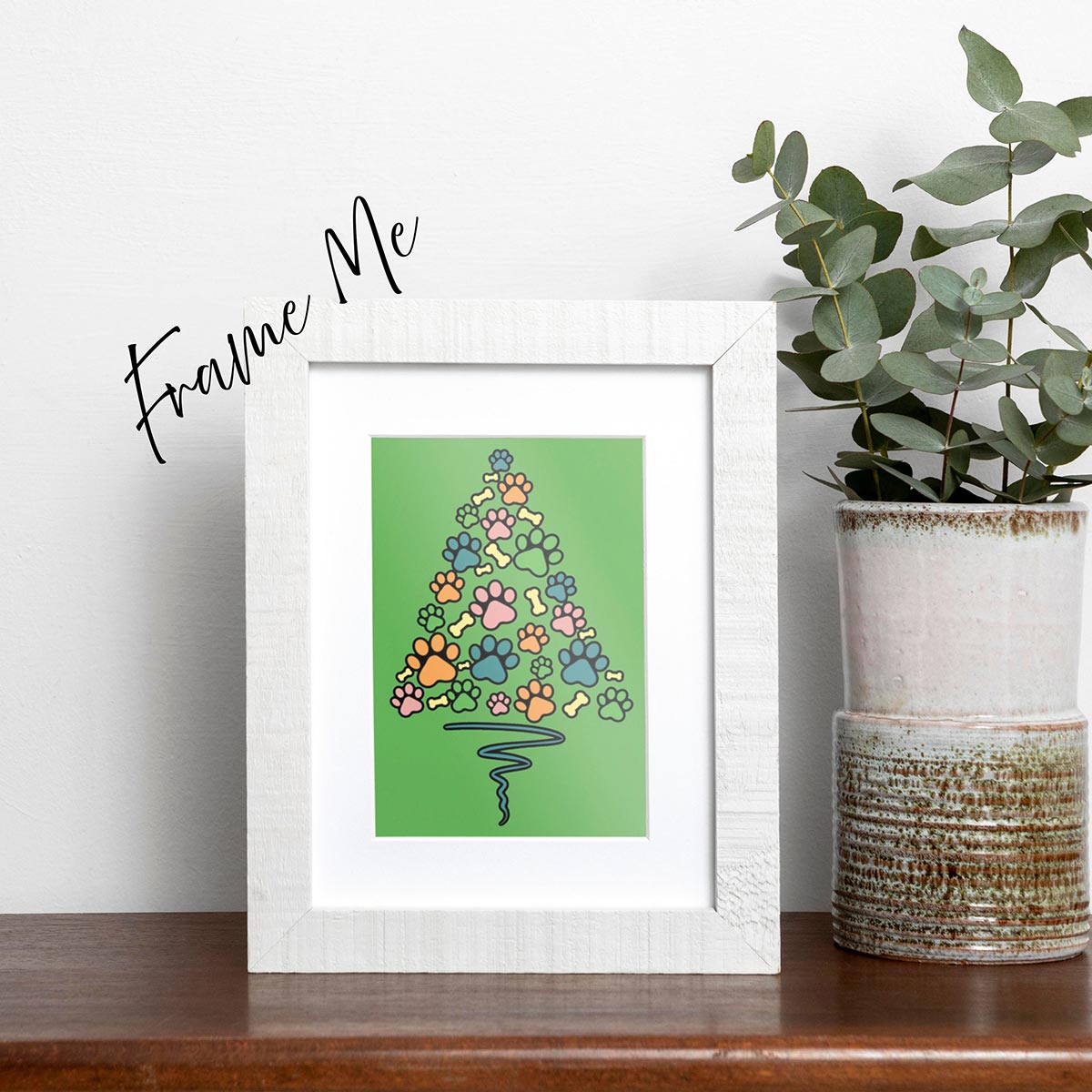 framed Paw Print Christmas Tree card featuring blue orange pink green paws and yellow bones shaped like a Christmas Tree with a blue wavy line as the tree trunk on a green background, frame is not included with purchase