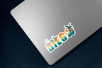Sticker design with the words 'San Diego' in a bold gradient font transitioning from teal to yellow to orange, resembling a sunset. The word 'San' is written in a teal script font above the 'D' in 'Diego'. The 'O' is replaced with a large paw print in matching gradient colors, overlaid with a silhouette of a palm tree. The design is outlined in white. The sticker is on a silver laptop.