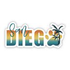Sticker design with the words 'San Diego' in a bold gradient font transitioning from teal to yellow to orange, resembling a sunset. The word 'San' is written in a teal script font above the 'D' in 'Diego'. The 'O' is replaced with a large paw print in matching gradient colors, overlaid with a silhouette of a palm tree. The design is outlined in white.