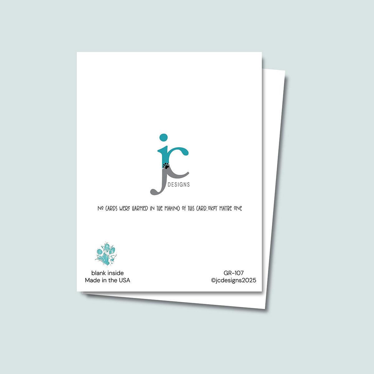 back of The Dog Ate It Birthday card showing JC Pet Designs logo and unique tagline message that reads "No cards were harmed in the making of this card, okay maybe one", in the bottom left corner is Oz's paw print in teal and text "blank inside, made in the USA", the sku and copyright @jcpetdesigns2025 are in the bottom right corner 