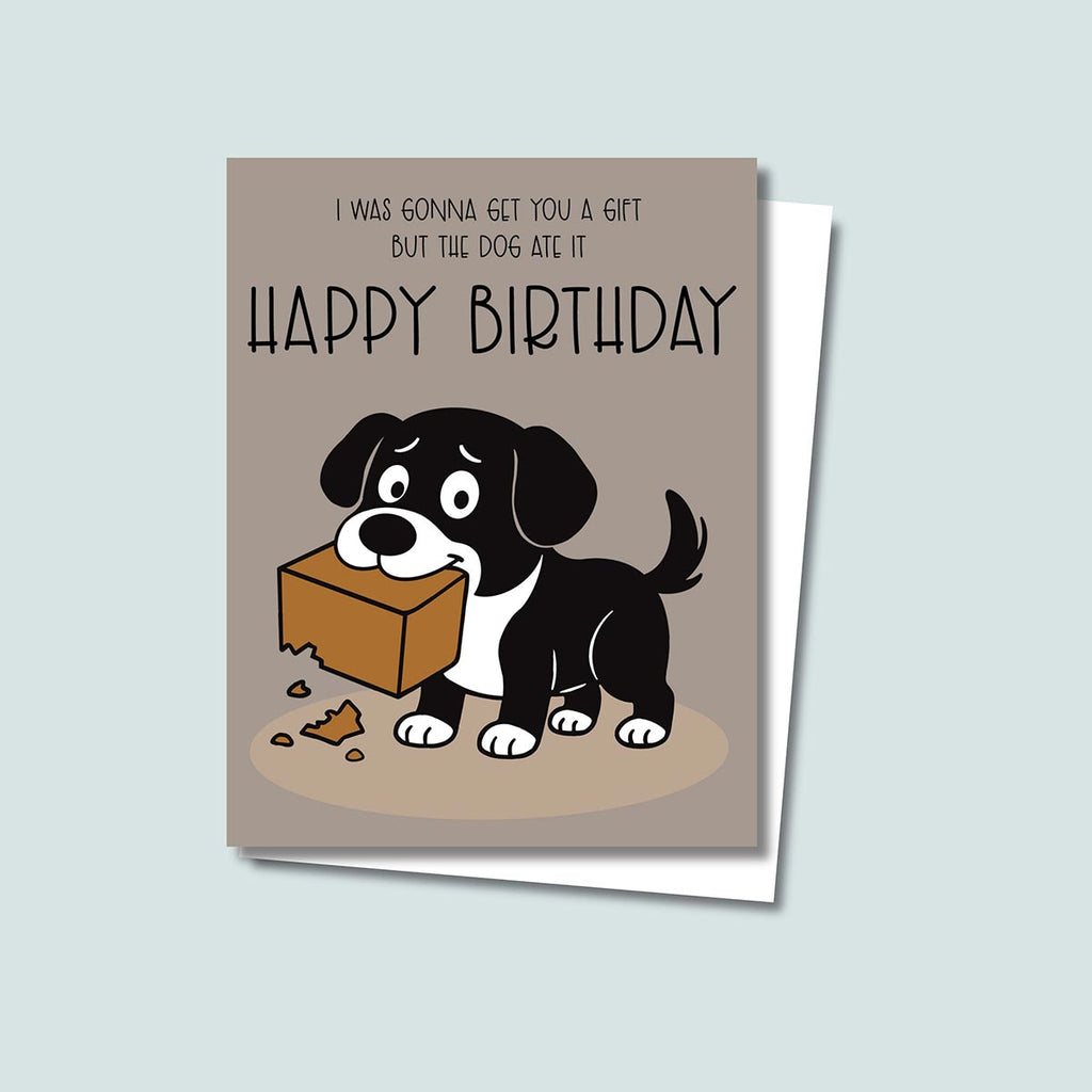 The Dog Ate It Birthday card featuring a cartoon black and white dog holding a chewed-up gift box with the text that reads, "I was gonna get you a gift but the dog ate it, Happy Birthday", the card is on a brown background