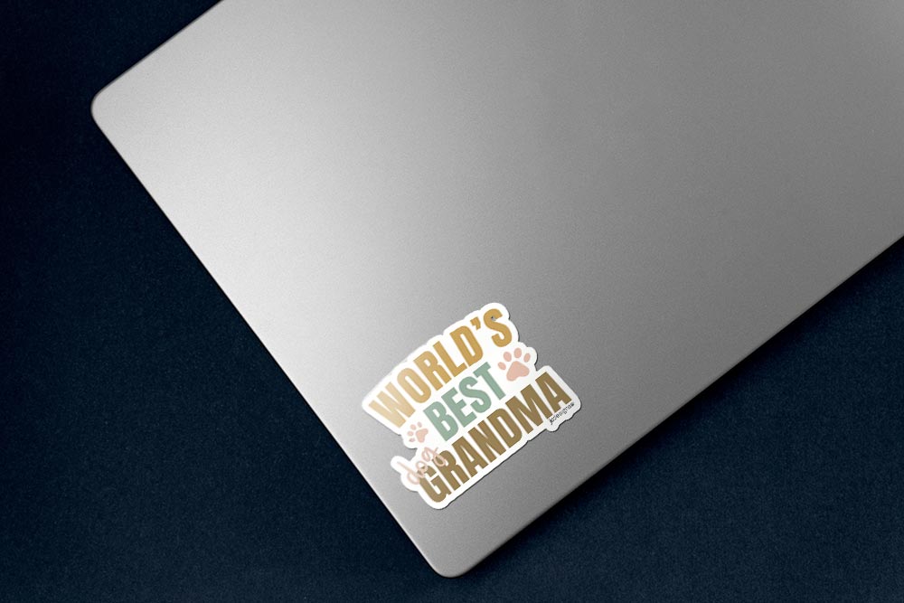 World’s best dog grandma sticker with playful typography and paw print accents in warm neutral tones, sticker on lower left corner of silver laptop