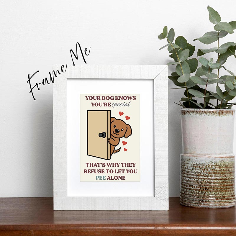 framed Illustrated greeting card showing a smiling dog peeking out from behind a door with hearts, reading “Your dog knows you’re special — that’s why they refuse to let you pee alone”
