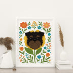 framed Brussels Griffon flower art print featuring a black and tan Griffon dog's face framed by a yellow flower surrounded by orange and teal flowers and green leaves and stems on a white background, frame not included with purchase