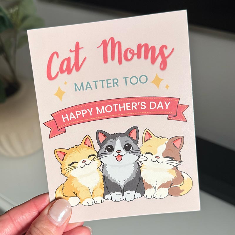 hand holding Illustrated Mother’s Day card featuring three smiling cats with the text “Cat Moms Matter Too – Happy Mother’s Day”