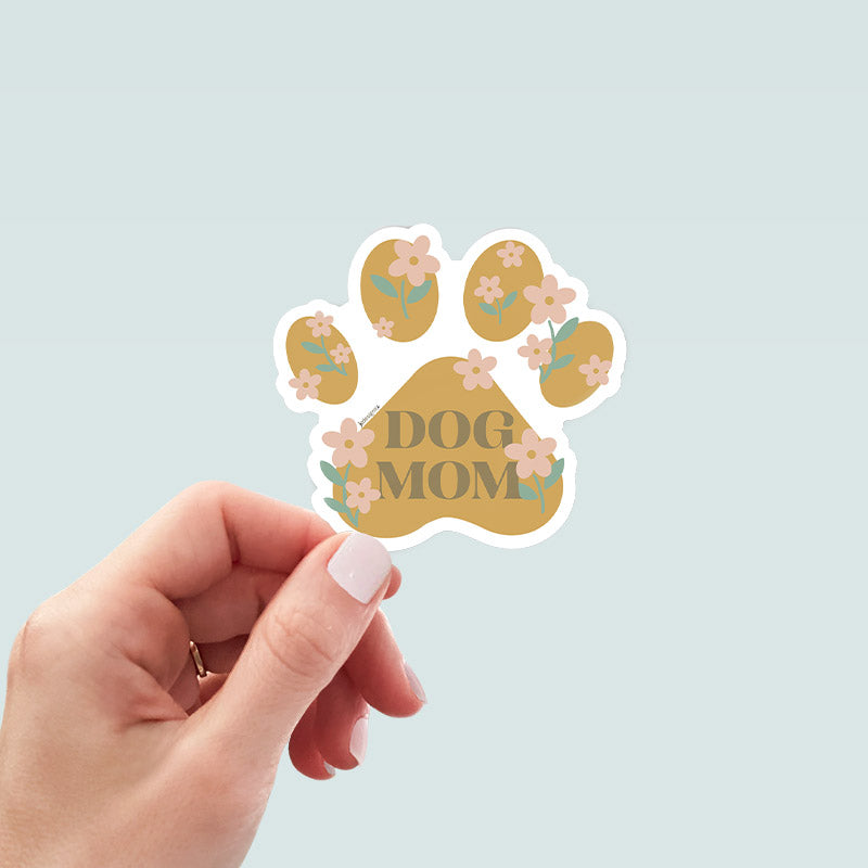 Hand holding dog mom paw print sticker with soft floral illustrations and neutral pastel colors, celebrating dog moms