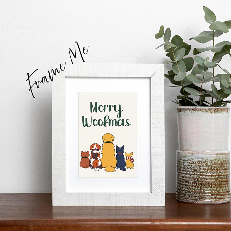 Framed print with 'Merry Woofmas' text and dog illustrations on a shelf with a plant.