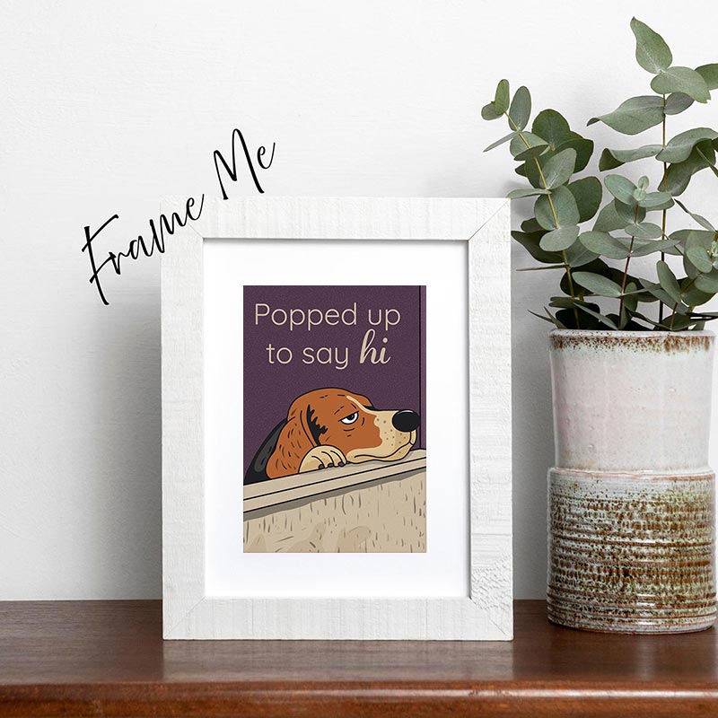 framed Illustrated greeting card of a dog popping up over a wall with the text “Popped up to say hi”