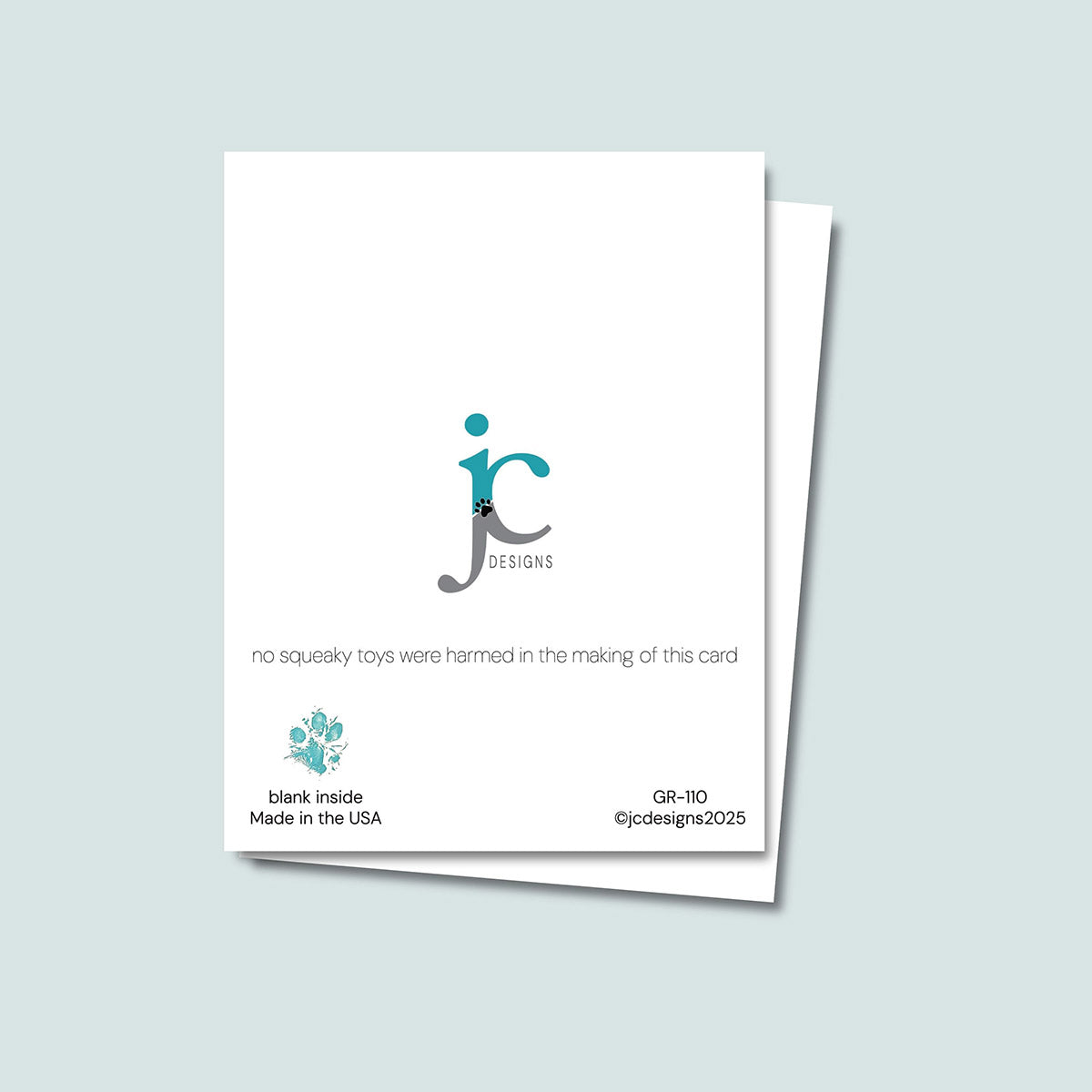 back of Squeaky Toys birthday card showing JC Pet Designs logo and a unique tagline that reads "no squeaky toys were harmed in the making of this card", in the bottom left corner of the card is Oz's paw print in teal, and text that reads "blank inside, made in the USA", the sku and copyright @jcpetdesigns 2025 is on the bottom right corner of the card