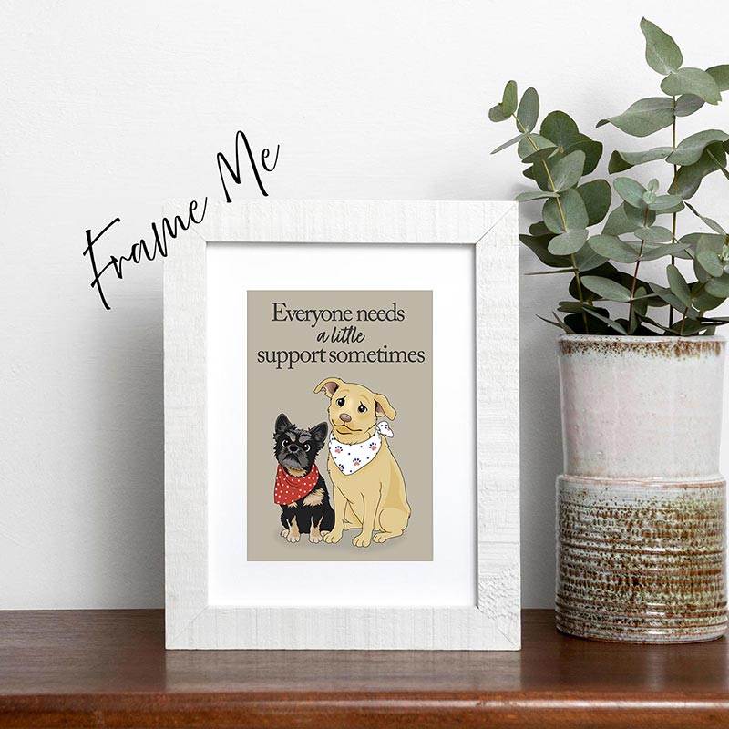 Framed hand-drawn card with two dogs and text 'Everyone needs a little support sometimes' on a shelf with a plant. Frame Not included with purchase.